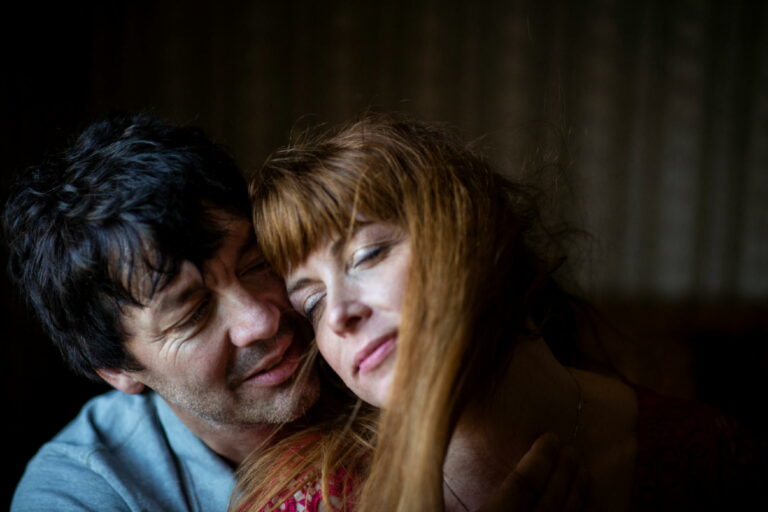 Mann umarmt Partnerin von hinten, Online-Paar-Psychotherapie, Unternehmen